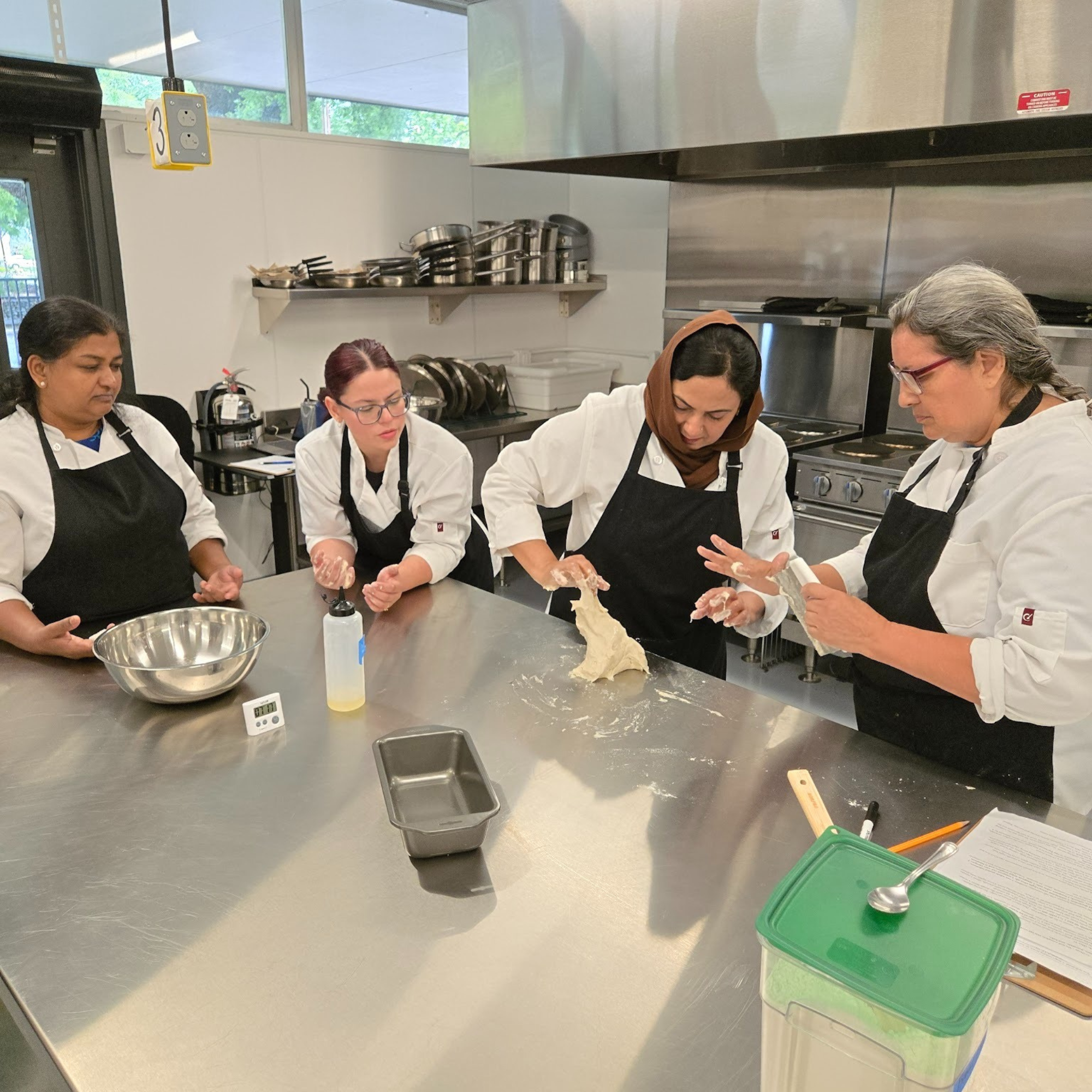 Four women culinary students learning to work with dough.