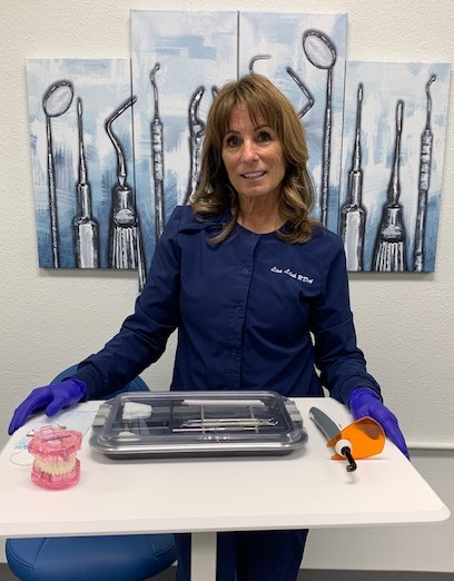 Dental assistant instructor standing behind a tray with dental tools and teeth model.