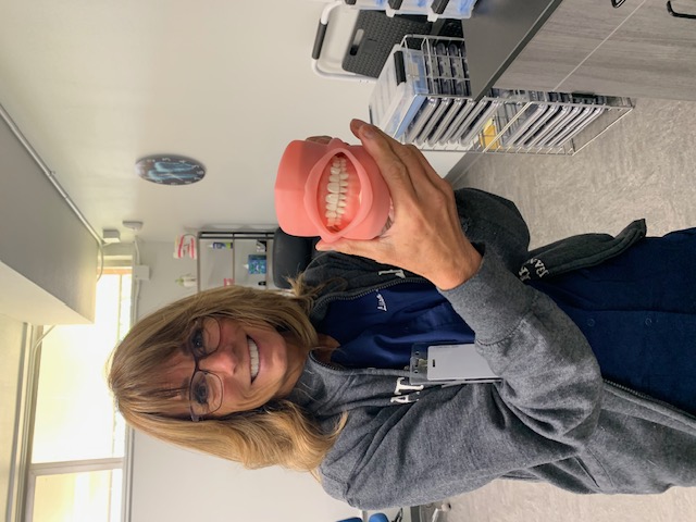 Dental Assisting Instructor holding a model of a full set of teeth.